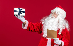 Санта Клаус с письмом на красном фоне