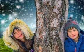 Мальчик и девочка стоят у дерева зимой