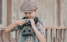 Мальчик в кепке с фотоаппаратом в руках