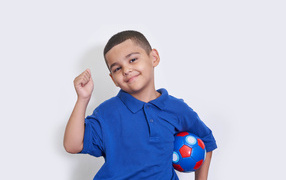 Boy soccer player with ball on gray background