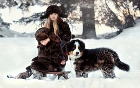 Children on a sled with a puppy in winter