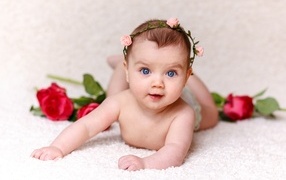 Cute blue-eyed baby girl with rose flowers