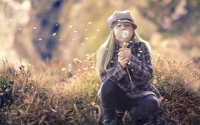 Girl in a cap blowing a dandelion