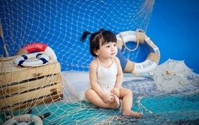 Маленькая девочка азиатка со  спасательным кругом и сетью 