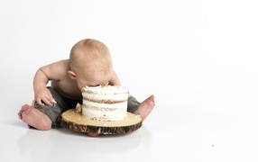 Little boy eating birthday cake on white background