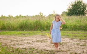 Маленькая девочка в платье с корзиной полевых цветов