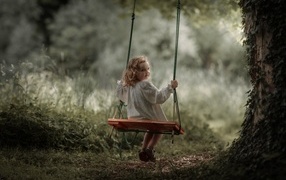 Little girl on a swing in the garden
