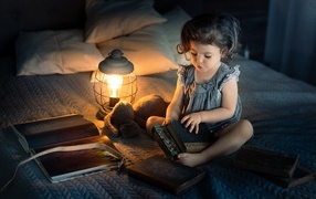 Little girl reading books on the bed