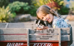 Маленькая девочка со щенком в тележке
