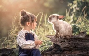 Маленькая девочка с кроликом в саду