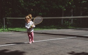 Little girl with a racket on the field
