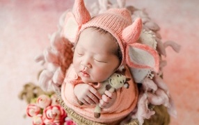 Маленький спящий новорожденный ребенок в шапке с рогами