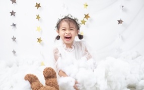 Маленькая улыбающаяся девочка азиатка в белом платье