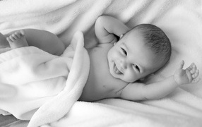 Маленький улыбающийся ребенок в белом покрывале