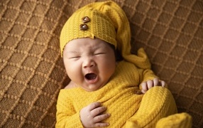 Little yawning child in a yellow suit