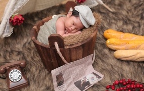 Новорожденный маленький мальчик в деревянном ведре на фотосессии 