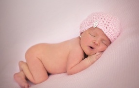 Розовая шапка на голове новорожденной девочки