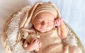 Спящий грудной ребенок в вязаном костюме