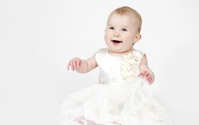 Улыбающаяся маленькая девочка в белом платье 