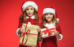 Две девочки в новогодних костюмах на красном фоне