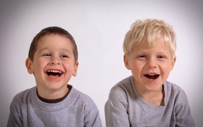 Two laughing little boys on a gray background