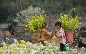 Two little Asian girls with baskets of yellow flowers