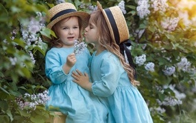 Two little girls in the garden with lilacs