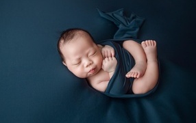 Новорожденный малыш в черном покрывале