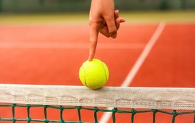 Finger holding a yellow tennis ball