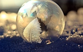 Frosty pattern on a soap bubble on the snow in winter