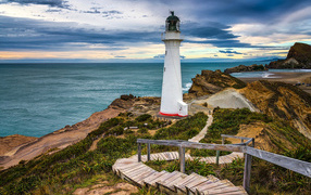 The lighthouse stands on the seashore on the coast of New Zealand