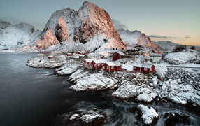 Snow-covered houses and a mountain near the water, Norway Lofoten Islands