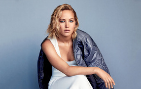 Actress Jennifer Lawrence in a jacket sits against the wall