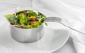 Green salad with nuts on a large white plate