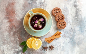 A cup of aromatic tea on the table with lemon, cookies and spices
