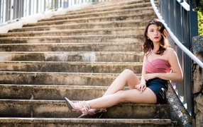 Cute slender Asian girl sitting on the steps