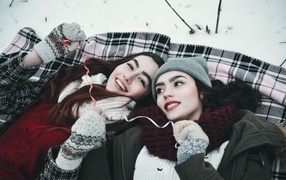 Two beautiful young girls lie on the snow