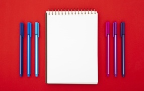 Notepad and markers on a red background