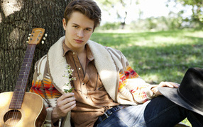Actor Ansel Elgort with a guitar near a tree