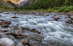 A fast cold river flows over rocks in the mountains