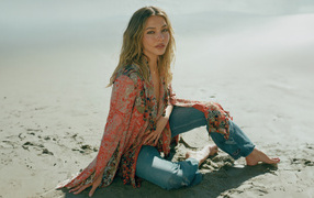 Actress Madeline Cline sits on the sand