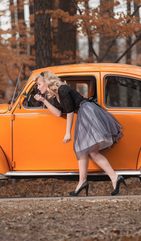 Девушка красит губы у зеркала старого автомобиля