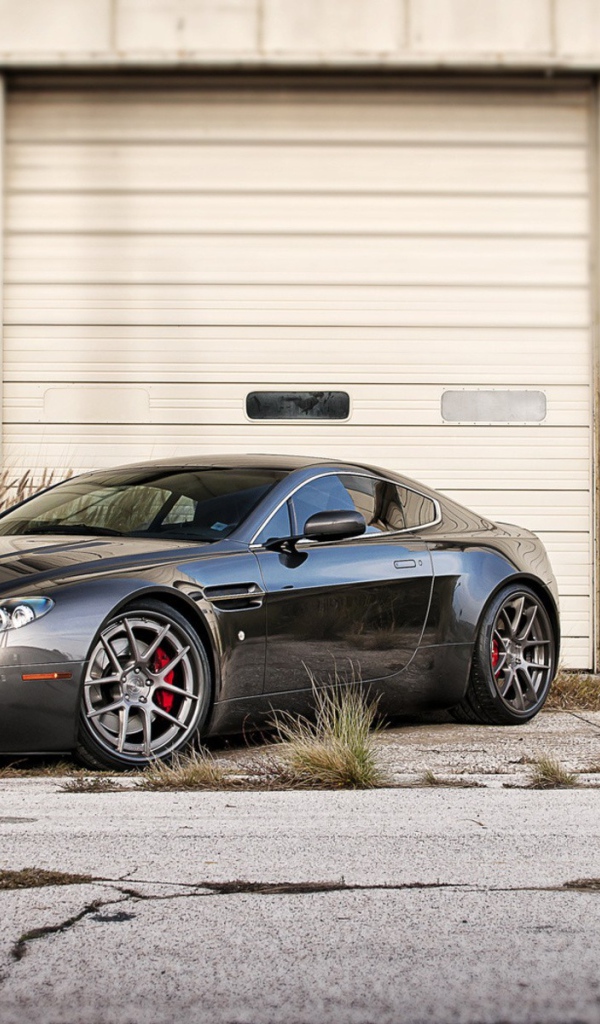 Черный Aston Martin в ворот белого ангара