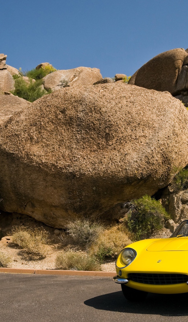 Старый желтый Ferrari у большого камня