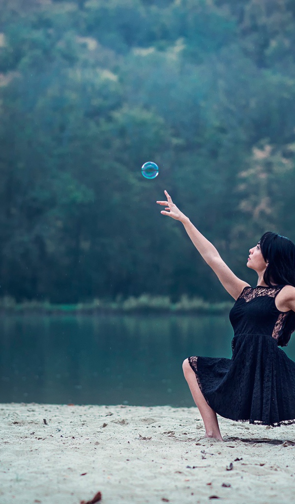 Девушка в черном платье и мыльный пузырь