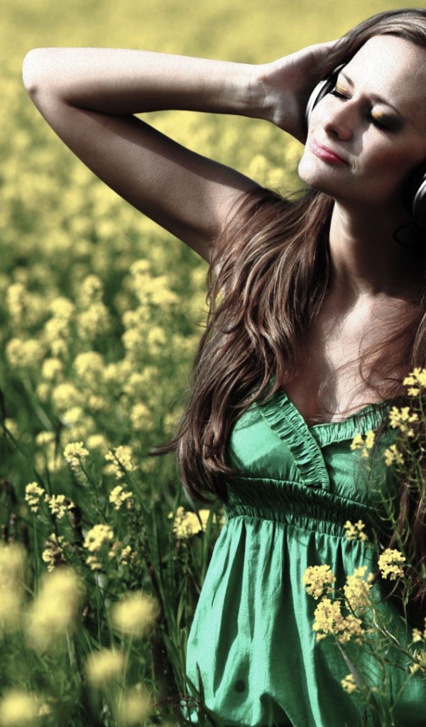 Девушка стоит среди цветов в наушниках