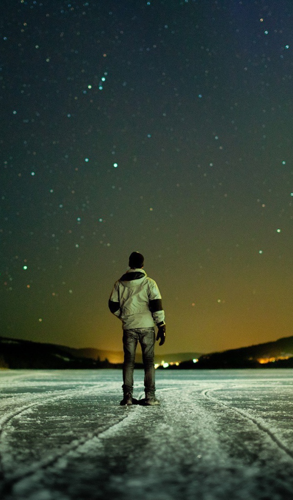 Мужчина на льду смотрит на звезды