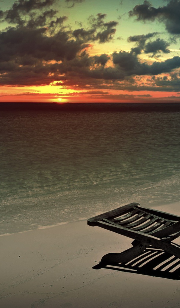 Черный шезлонг на закате на пляже