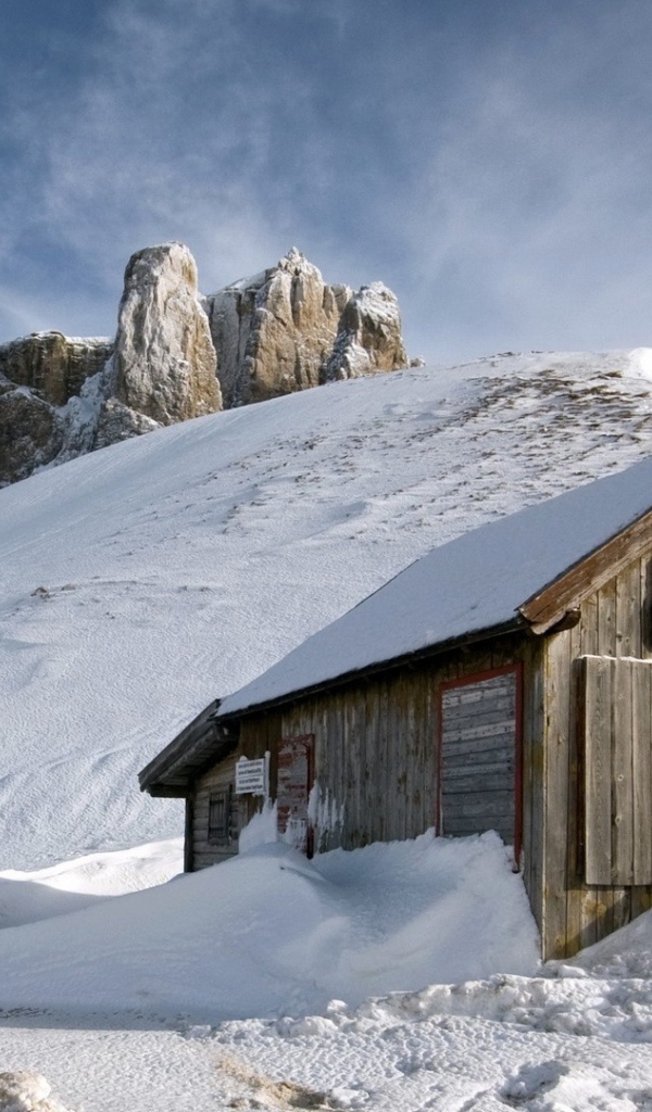 Деревянный домик замело снегом в горах
