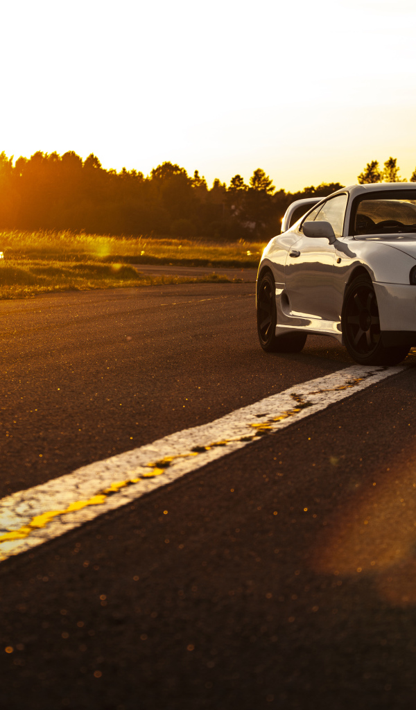 Белый автомобиль Toyota Supra стоит на трассе на рассвете